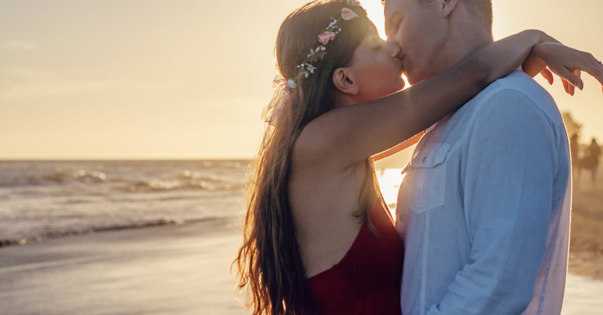 Young couple sharing a romantic kiss on a beach at sunset.
