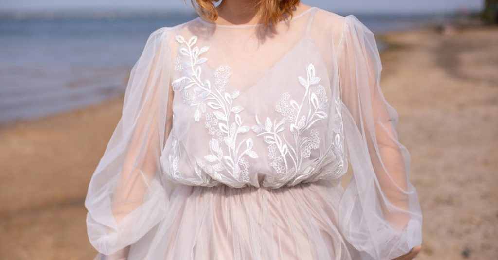 A stylish woman in a sheer white dress enjoys a sunny day at the beach.